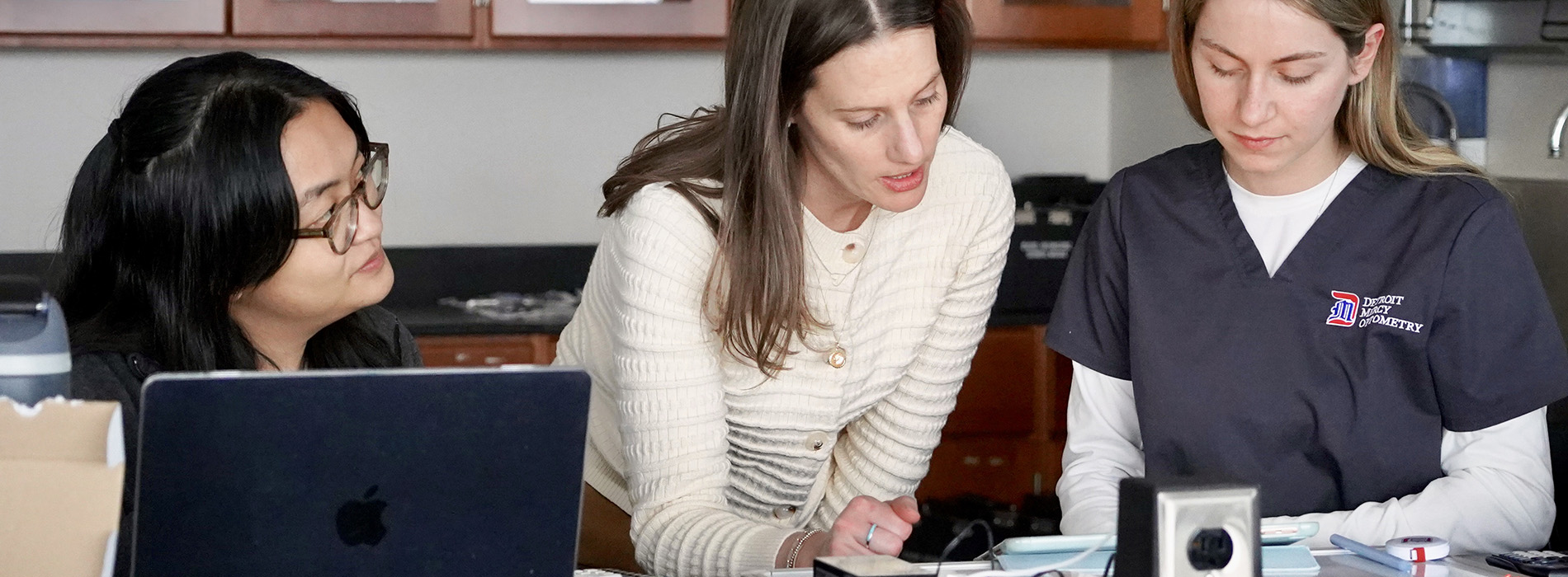 three students sitting before laptop